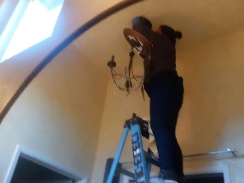 Electrician installing a chandelier in a Holton residence